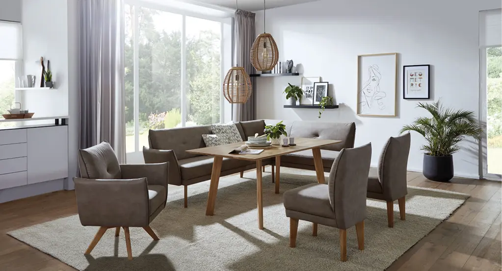 Esszimmer mit Holztisch, Eckbank, zwei Stühlen, Teppich und großen Fenstern